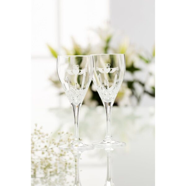 pair of galway crystal white wine glasses with claddaghs etched on them in front of flowers